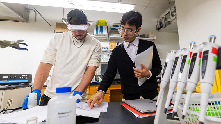 A chemistry professor instructs a student during a lab activity.